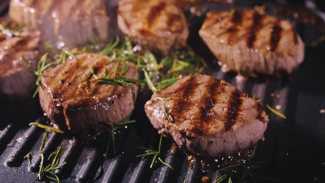 Delicious juicy meat steak cooking on grill. Aged prime rare roast grilling tenderloin fresh marble tenderness beef. Prime beef fry on electric roaster, rosemary, black pepper, salt. Slow motion.