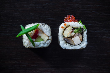 Sushi rolls with caviar, green onion, philadelphia, cucumber, omelette top view on black tableboard. Japanese food concept. Still life close up food photo