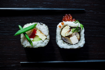 Sushi rolls with caviar, green onion, philadelphia, cucumber, omelette top view on black tableboard. Japanese food concept. Still life close up food photo