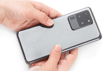 Smartphone with a broken back cover in hands on a white background.