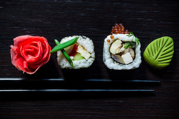 Sushi rolls with caviar, ginger, wassabi and chopsticks top view on black tableboard. Japanese food concept. Still life close up food photo