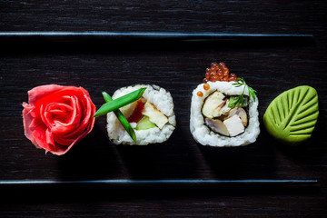 Sushi rolls with caviar, ginger, wassabi and chopsticks top view on black tableboard. Japanese food concept. Still life close up food photo
