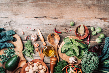 Fresh green kale, spinach, avocado, nuts, pepper, greens, salt, spices, oil on rustic wooden...