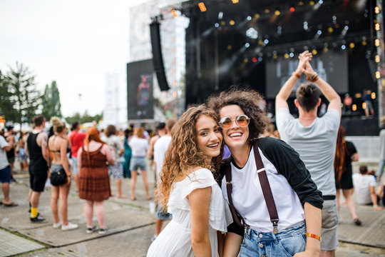 Young girl friends at summer festival, posing for photograph.