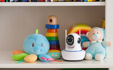 IP camera on the shelf with toys, serving as a baby monitor