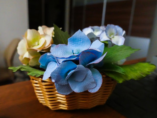Decorative flowers in a wicker basket. Wicker planters with artificial flowers in white and blue for home decor.