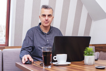 Businessman having coffee in a cafe while working on laptop