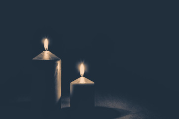 burial concept with two golden burning candles against black background