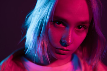 Portrait of unusual beautiful glamour and fashion girl with colorful hairstyle on studio background. Young woman in pink and violet neon light. 