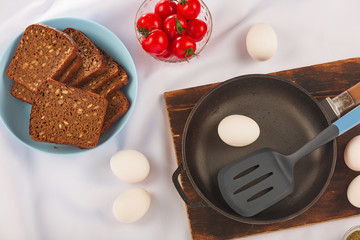 Healthy breakfast background with eggs, herbs, cherry tomatoes and dark bread