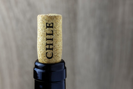 Bottle neck with a cork on a wooden background. Name of the wine country Chile is written on cork.