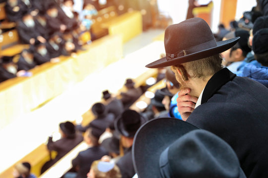 Orthodox pilgrims of Hasidim listen to their rabbi during mass prayer in In a synagogue.