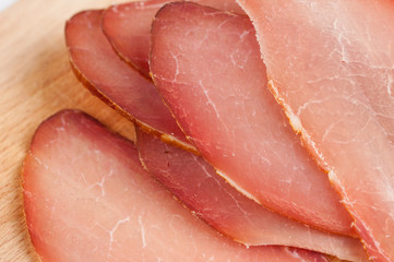 Delicious smoked meat on a wooden board isolated on white background.Copy space