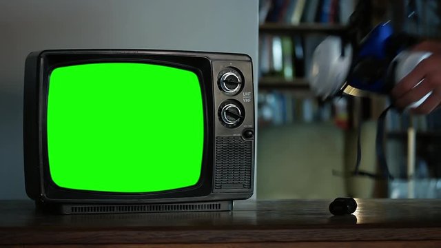 Hand picking up a Face Respirator Mask and a Retro TV with Green Screen. Close-Up. You can Replace Green Screen with the Footage or Picture you Want with “Keying” effect in After Effects.
