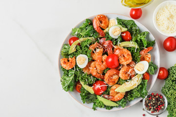 Plate of healthy diet fresh salad made of shrimps, kale, avocado, tomatoes, eggs and cheese for lunch. top view