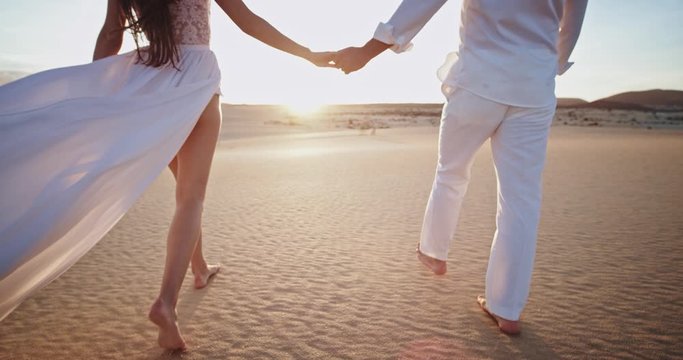 Amazing couple in love in the middle of the beach side they walking around holding hands in amazing sunset time