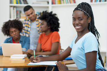 Laughing african american young adult with dreads and group of students
