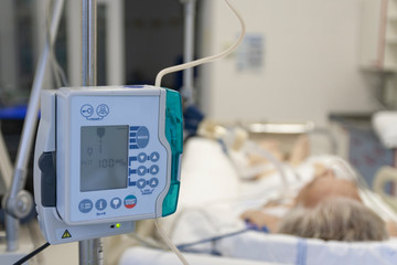 A small, lightweight, portable enteral feeding pump in ICU in hospital, on background patient in...