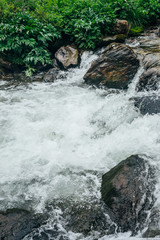 Beautiful landscape with big stones in water riffle of mountain river. Powerful water stream among boulders in mountain creek with rapids. Fast flow among rocks in highland brook. Small river close-up