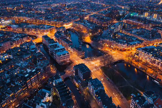 Amsterdam Netherlands aerial view at night. Old dancing houses, river Amstel, canals with bridges, old european city landscape from above. © DedMityay