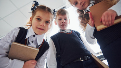 School kids in uniform posing for a camera together in corridor. Conception of education
