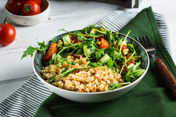 plate of fresh salad with arugula, bulgur, cherry tomatoes and avocado, decorated with microgreen. Horizontal photo with copy space, top view. healthy food concept. diet food. vegetarian food concept.
