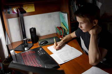 A child in front of a computer. The boy is doing homework. Distance learning in quarantine.
