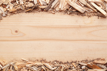 Wood chips biomass arranged in stripes on top and bottom of image on wood spruce background. Top view with copy space. Flat lay.