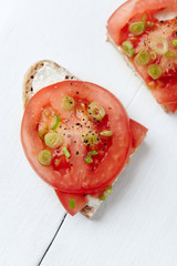 Sandwich with soft cheese and tomatoes. Bright wooden background. Top view.	
