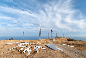 Dilapidated wind power station with spare parts of wind turbines in the foreground