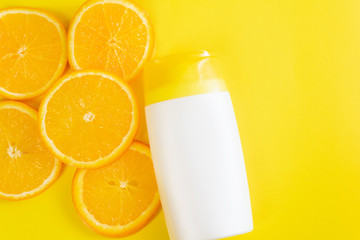 Sunscreen on a yellow background with slices of orange. Cosmetic beauty product branding mock-up for moisturizing cream, lotion, serum or essential oil. Top view