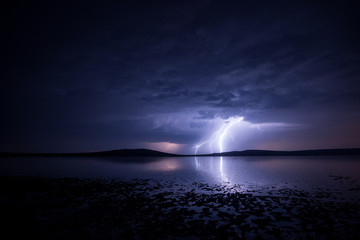 Fototapeta na wymiar Massive triple lightning over the lake with reflection