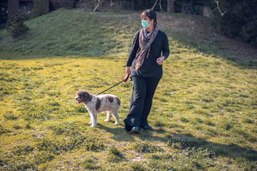 woman walking dog in the park with face mask