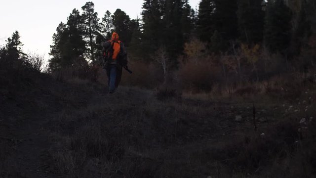 Father and Son Hunters walk up trail in early morning light. Handheld 4K