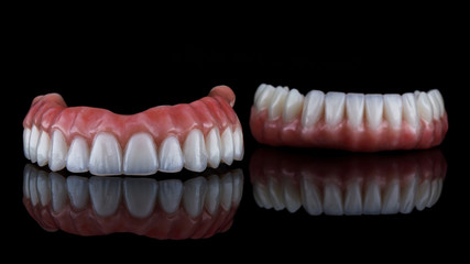 beautiful dental prosthesis for the upper jaw in the foreground, shot on a black background with reflection