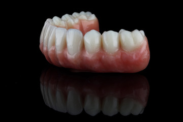 dental lower jaw prosthesis with pink gum on black glass, side view