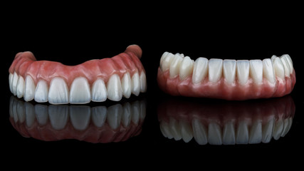 two dental prostheses of the lower and upper jaws on a black background with perfect reflection