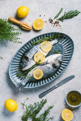 Seafood concept. Cooking dorado or sea bream fish with lemon, herbs, oil, vegetables and spices on concrete background. Top view. Healthy food concept. Copy space. Food pattern