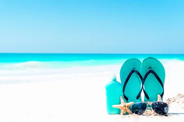 Fototapeten Suncream bottles, goggles, starfish and sunglasses on white sand beach background ocean © travnikovstudio