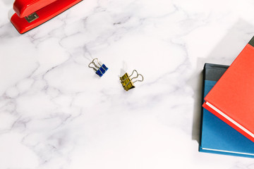 Naklejka premium Office work desk flat lay with books, paper clips, and stapler on marble surface with copy space
