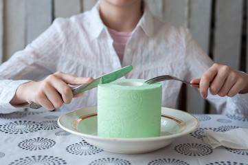 A roll of toilet paper lies on a plate. Girl wants to eat it with a knife and fork.