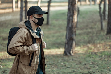 man in medical mask walking in park away from people. man breath fresh air outdoor