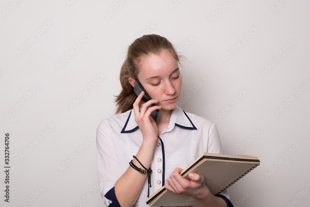 Wall mural young girl student. pretty young girl secretary. girl holds documents and talks on the phone.