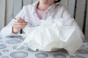 Pieces of toilet paper lie on a plate. Girl wants to eat it with a spoon