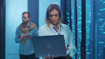 Woman IT administrator checking rack server hardware doing transparent data transfer working on...