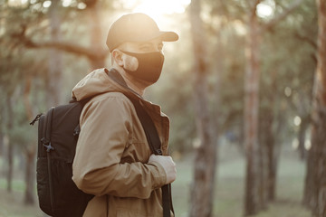 confident man in medical mask walks through park with backpack