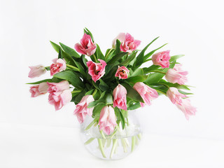 Beautiful bouquet of tulips in glass vase on the white background