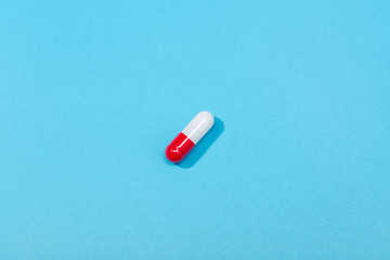 Fototapeta na wymiar Medical pill capsule isolated on blue background. Medicine, healthcare or pharmacy concept