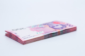 A lot of new banknotes in denominations of 200 Ukrainian hryvnias isolated on a white background with shadow. European money exchange. Ukraine currency. Selective focus