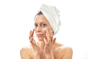 A young woman cares for her face and smears cream. White isolated background.